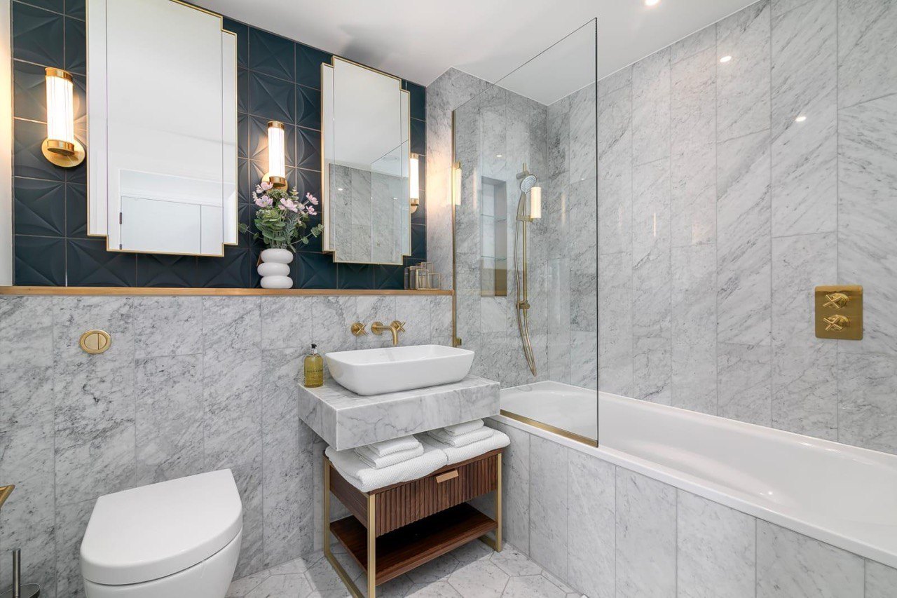 Marble bathroom with bath, brass fittings and mirrored cabinets, renovated by MALCON in a London apartment