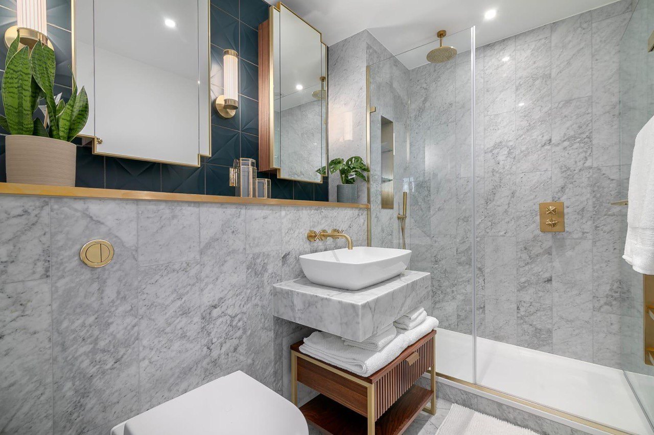 Marble and brass bathroom with walk-in shower and stone basin, renovated by MALCON in a London apartment