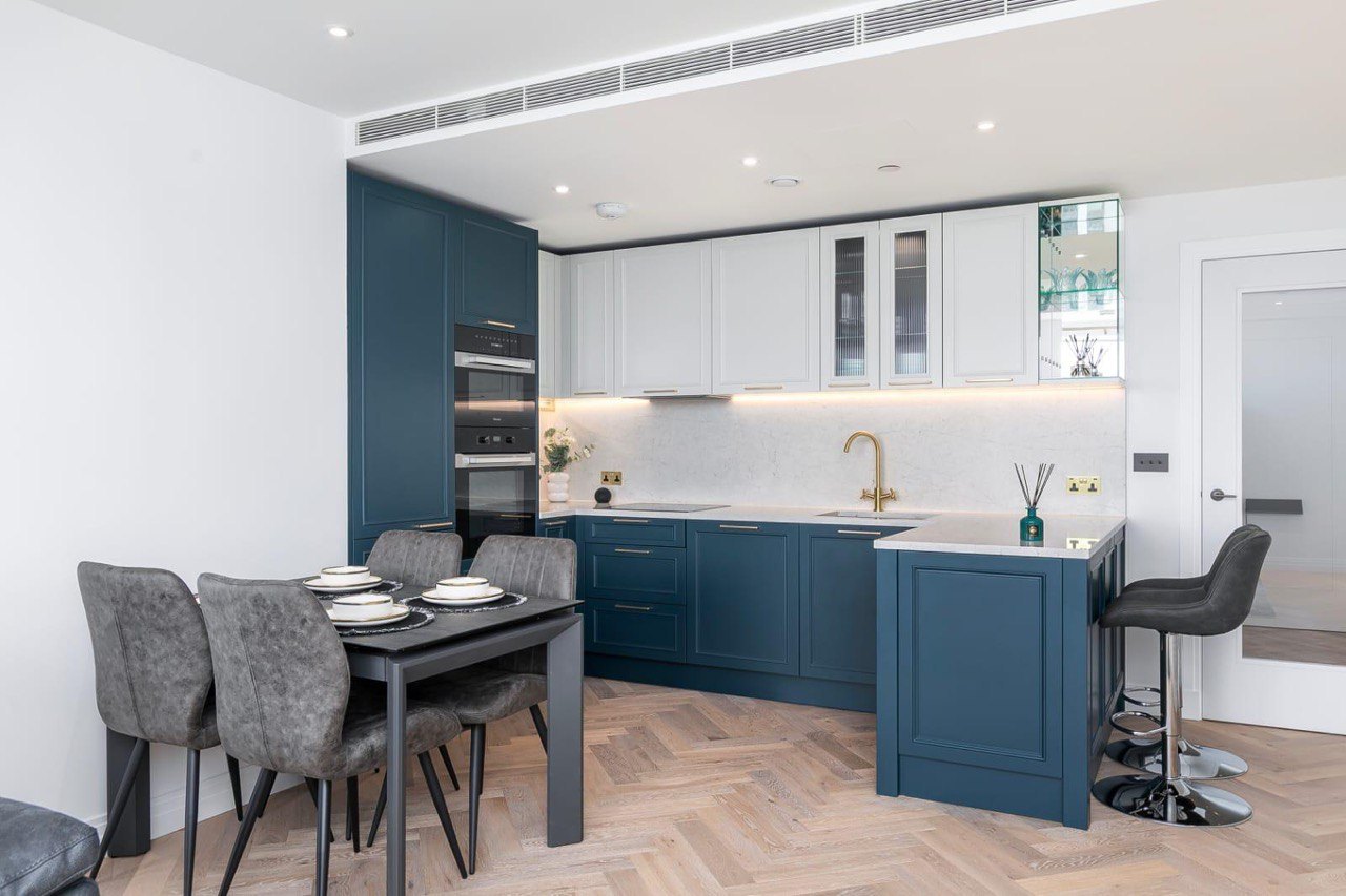 Navy Shaker-style kitchen with brass tap, glazed wall units and breakfast bar, renovated by MALCON in a London apartment