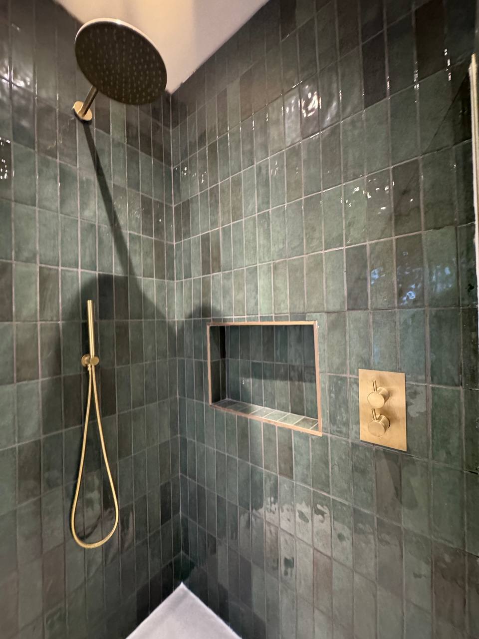 Walk-in shower with green glazed tiles, tiled niche and brass fittings by MALCON