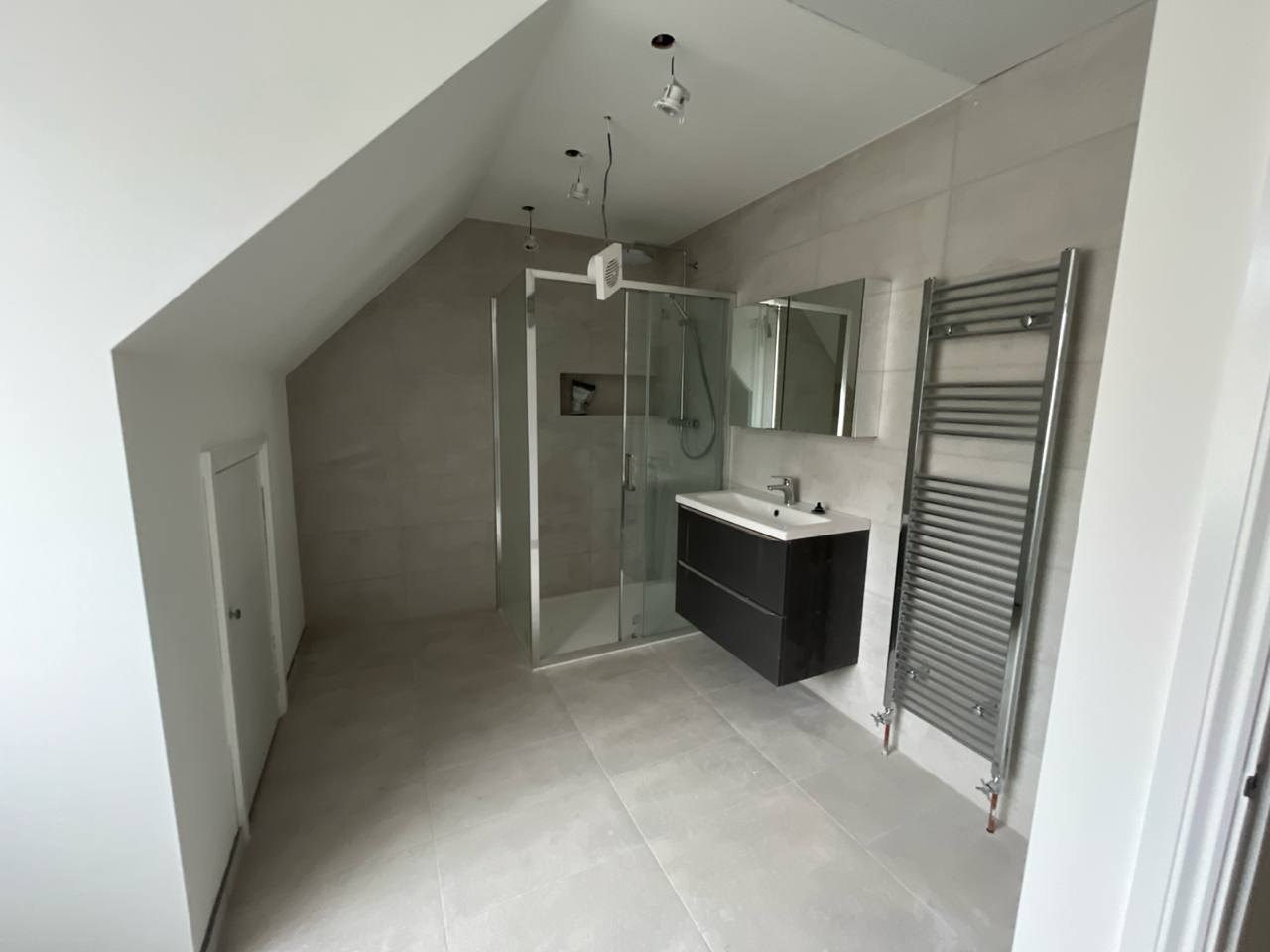 Loft shower room with walk-in shower, wall-hung vanity and towel radiator, completed by MALCON